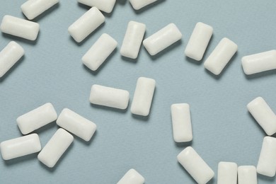 Photo of Tasty white chewing gums on light blue background, flat lay