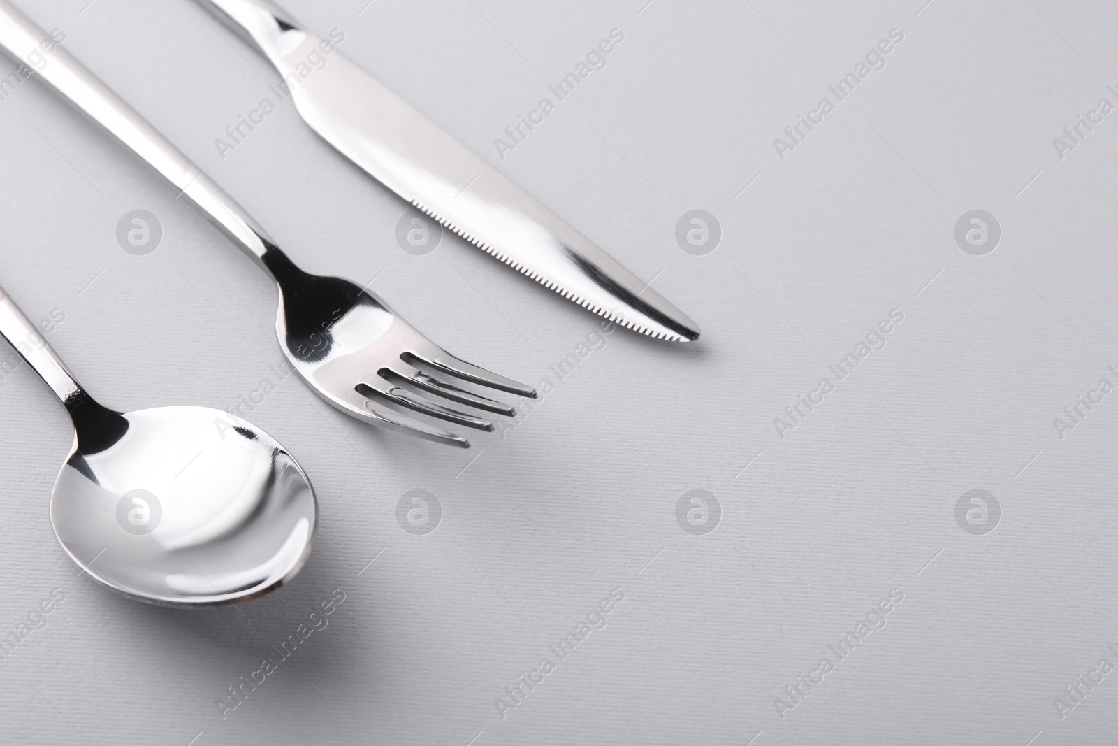 Photo of Stylish silver cutlery set on gray background, closeup. Space for text