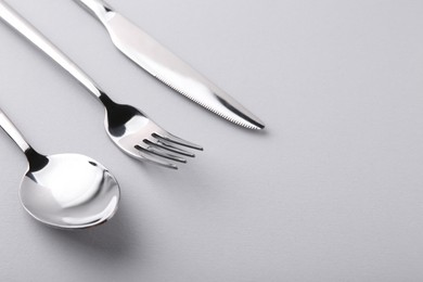 Stylish silver cutlery set on gray background, closeup. Space for text