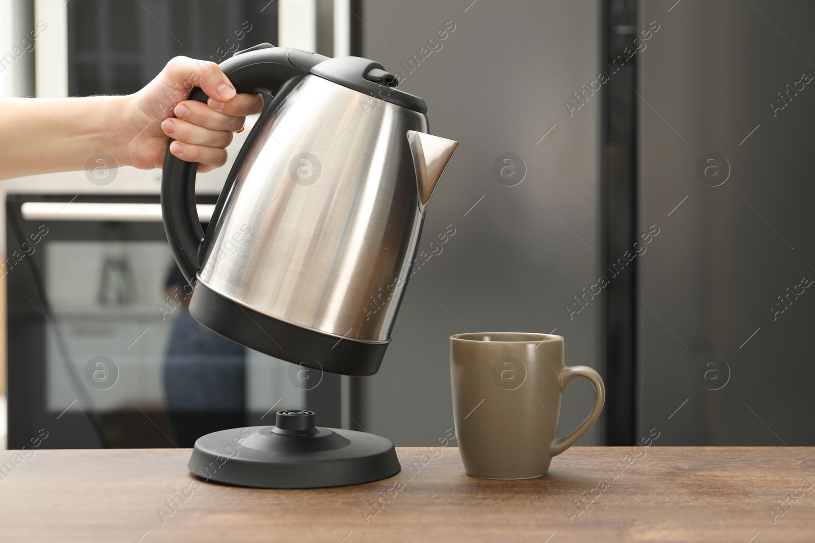 Photo of Woman with electric kettle in kitchen, closeup. Space for text