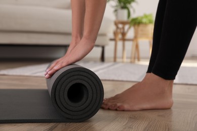 Woman unrolling yoga mat at home, closeup
