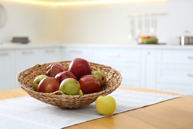 Photo of Fresh ripe apples and pears on wooden table in kitchen. Space for text