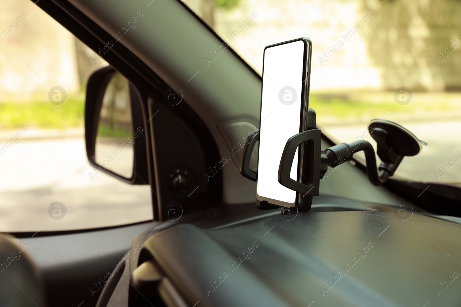 Photo of Car holder with modern mobile phone on windshield of automobile. Mockup for design