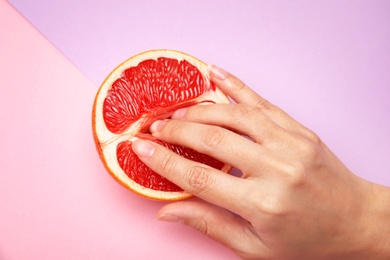 Young woman touching half of grapefruit on color background, above view. Sex concept