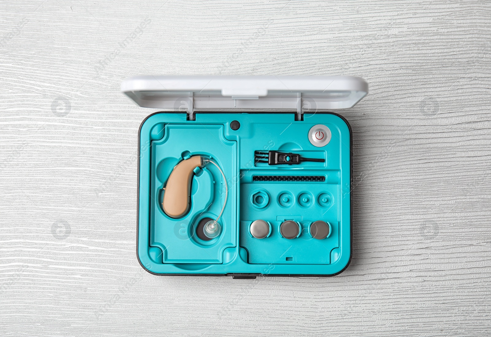 Photo of Case with hearing aid on white wooden background, top view