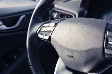 Black steering wheel inside of modern car, closeup