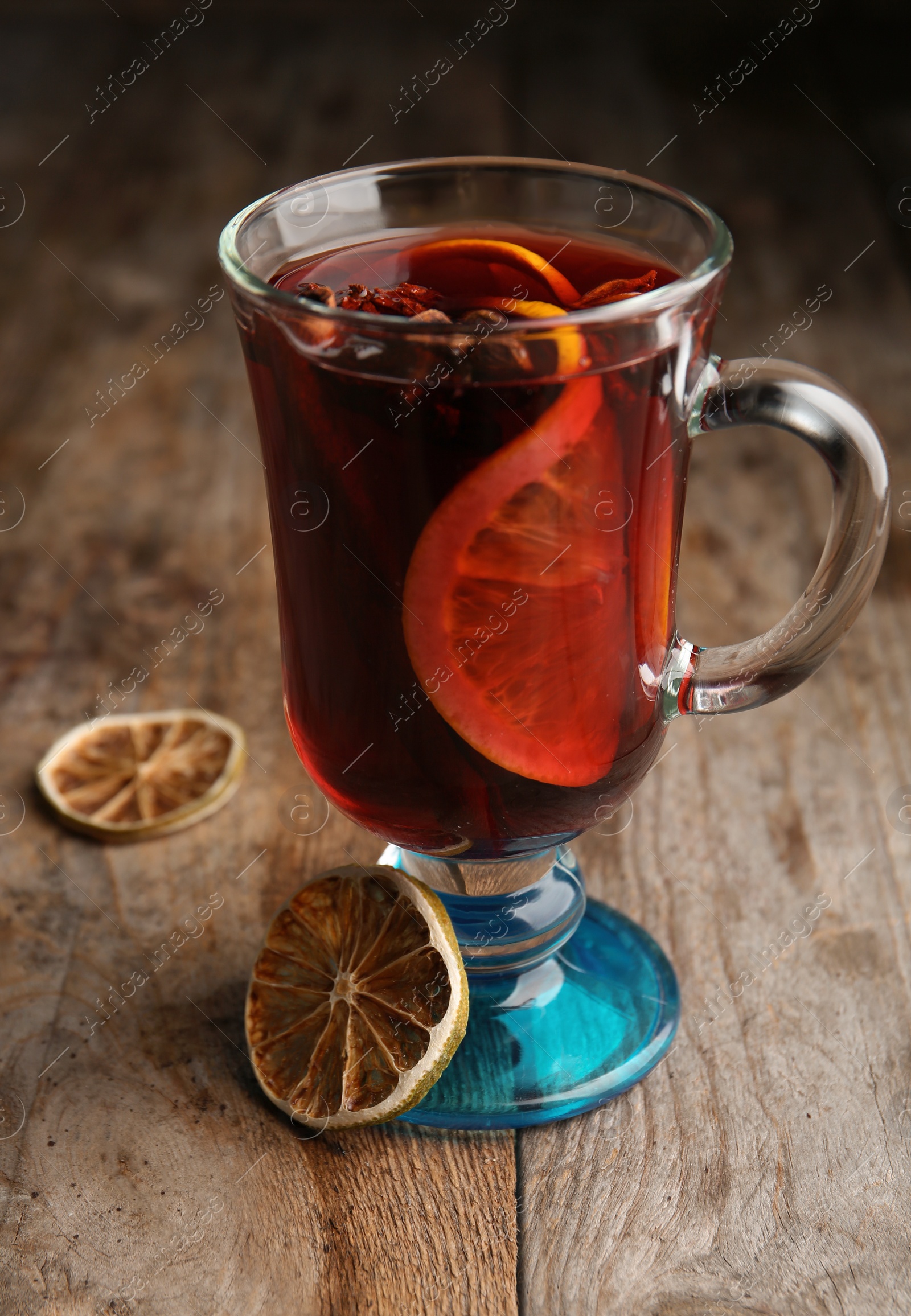 Photo of Glass with red mulled wine on wooden table