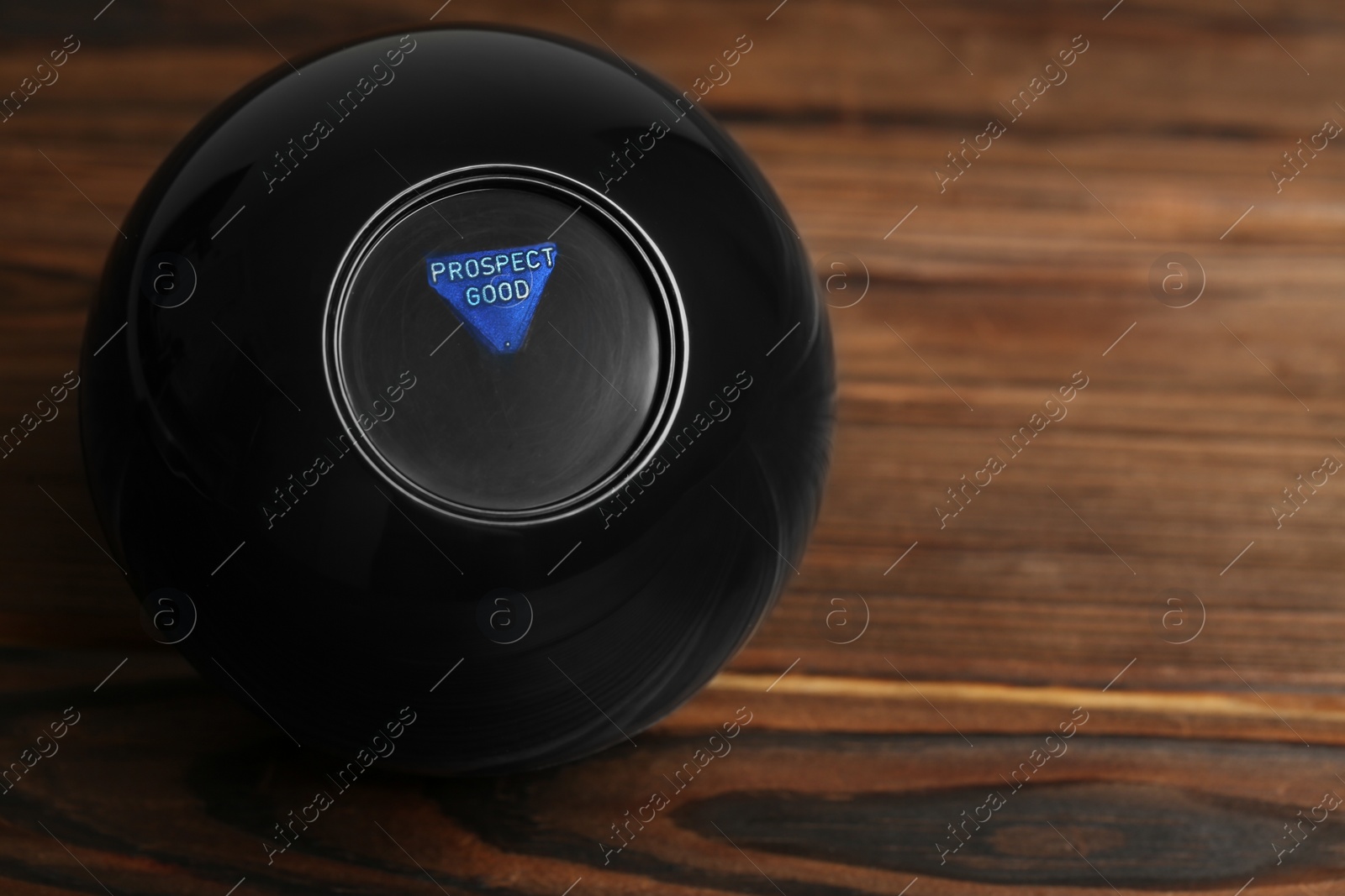 Photo of Magic eight ball with prediction Prospect Good on wooden table, space for text