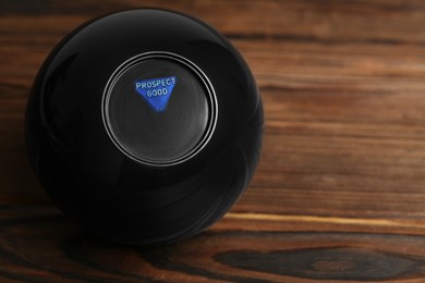 Photo of Magic eight ball with prediction Prospect Good on wooden table, space for text