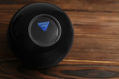 Magic eight ball with prediction Prospect Good on wooden table, space for text