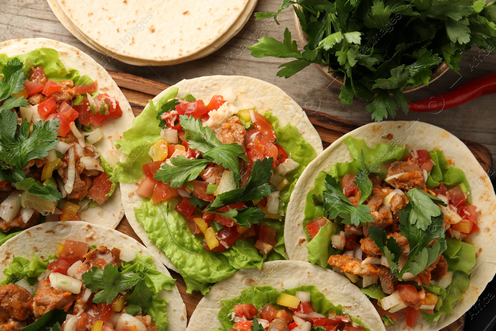 Photo of Delicious tacos with vegetables and meat on wooden table, flat lay