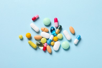Many different pills on light blue background, flat lay