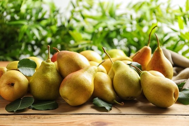 Photo of Ripe pears on wooden table against blurred background