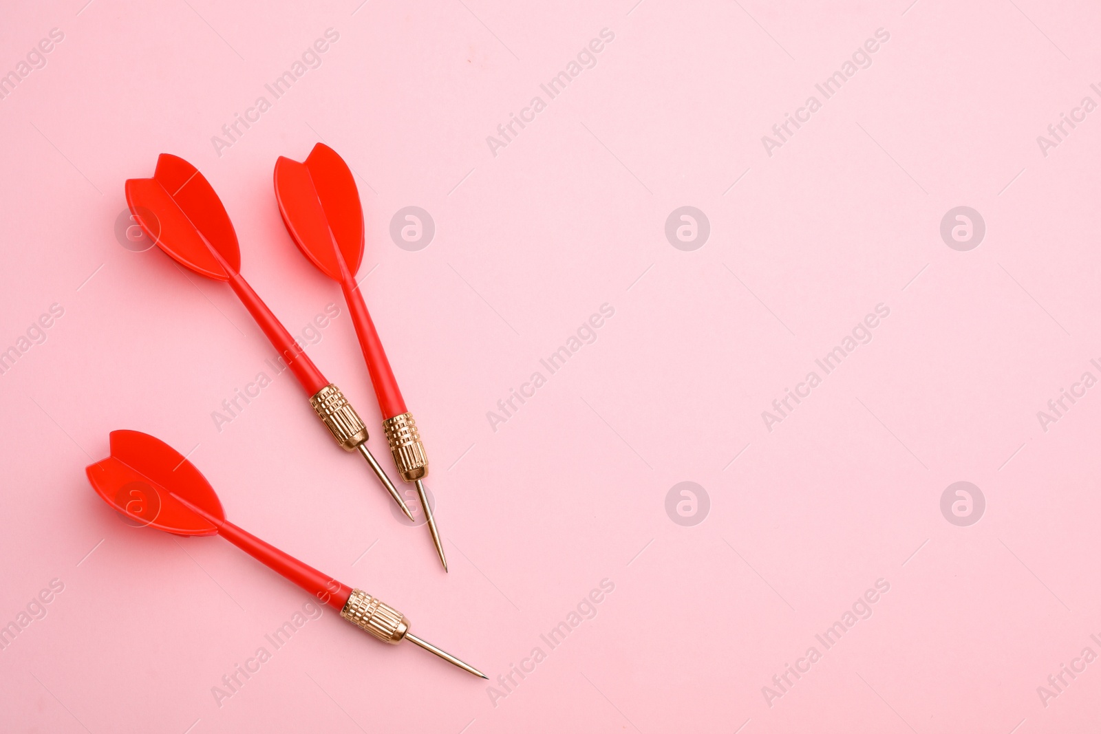 Photo of Red dart arrows on pink background, flat lay with space for text