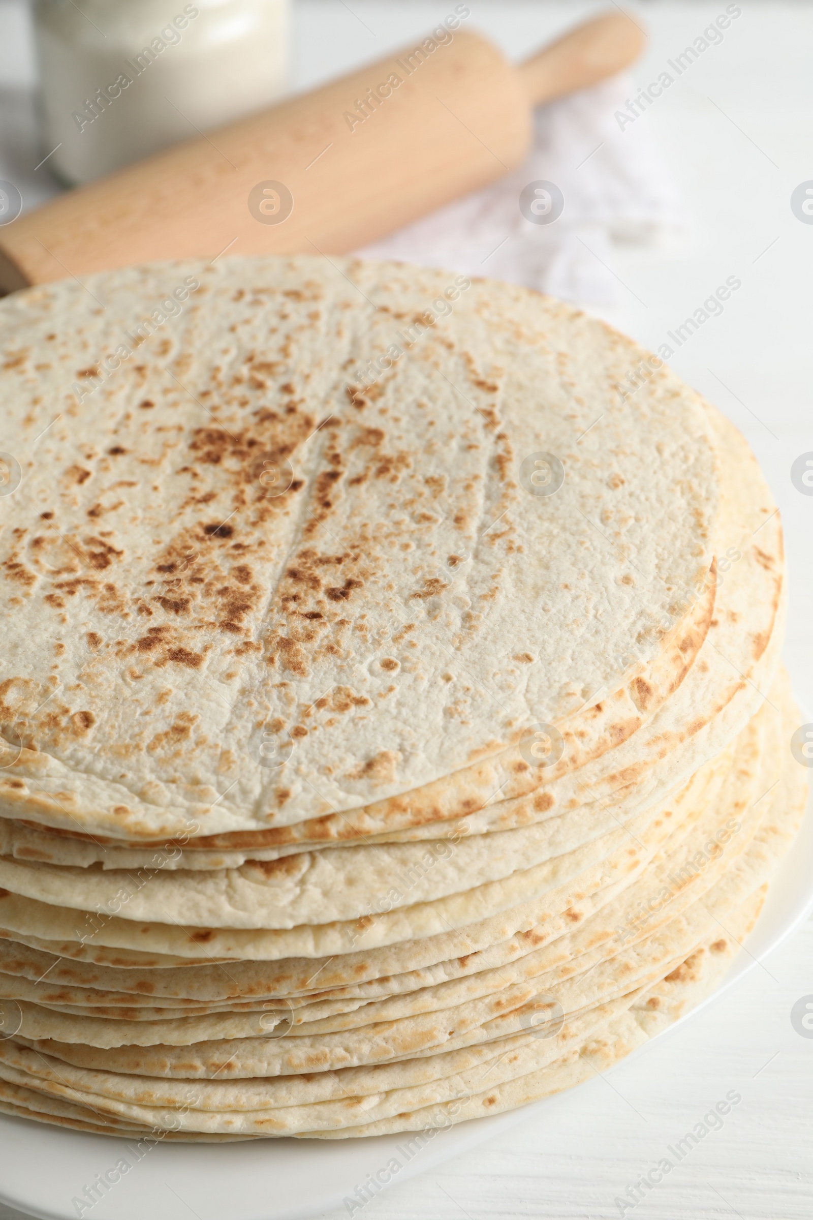 Photo of Tasty homemade tortillas and rolling pin on white table