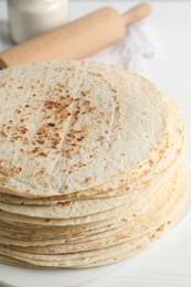 Photo of Tasty homemade tortillas and rolling pin on white table