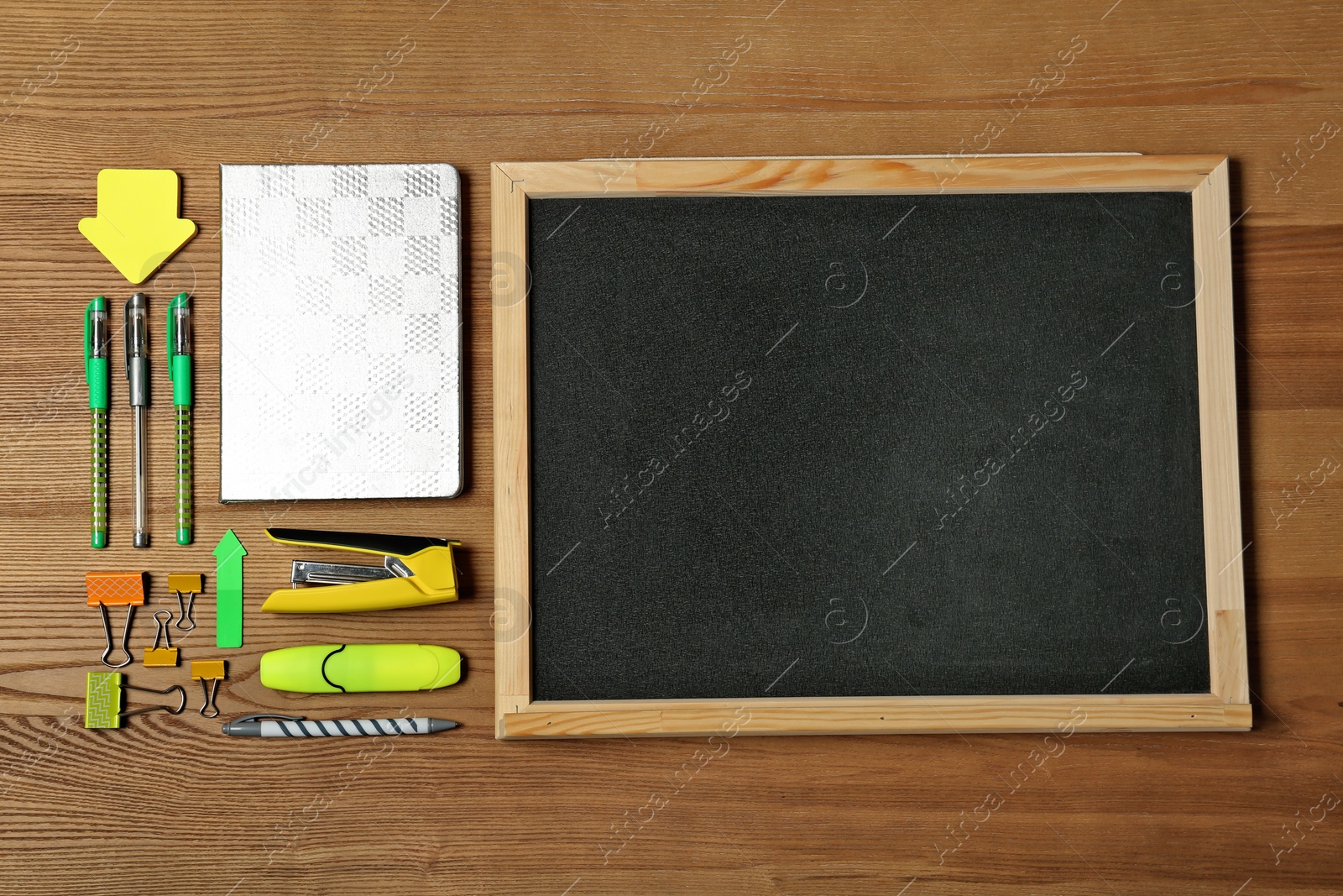 Photo of Flat lay composition with different school stationery and small chalkboard on wooden background