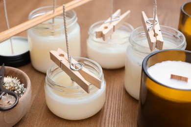 Photo of Glass jars with wax on wooden table. Handmade candles