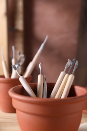 Photo of Set of different clay crafting tools on wooden table in workshop, closeup