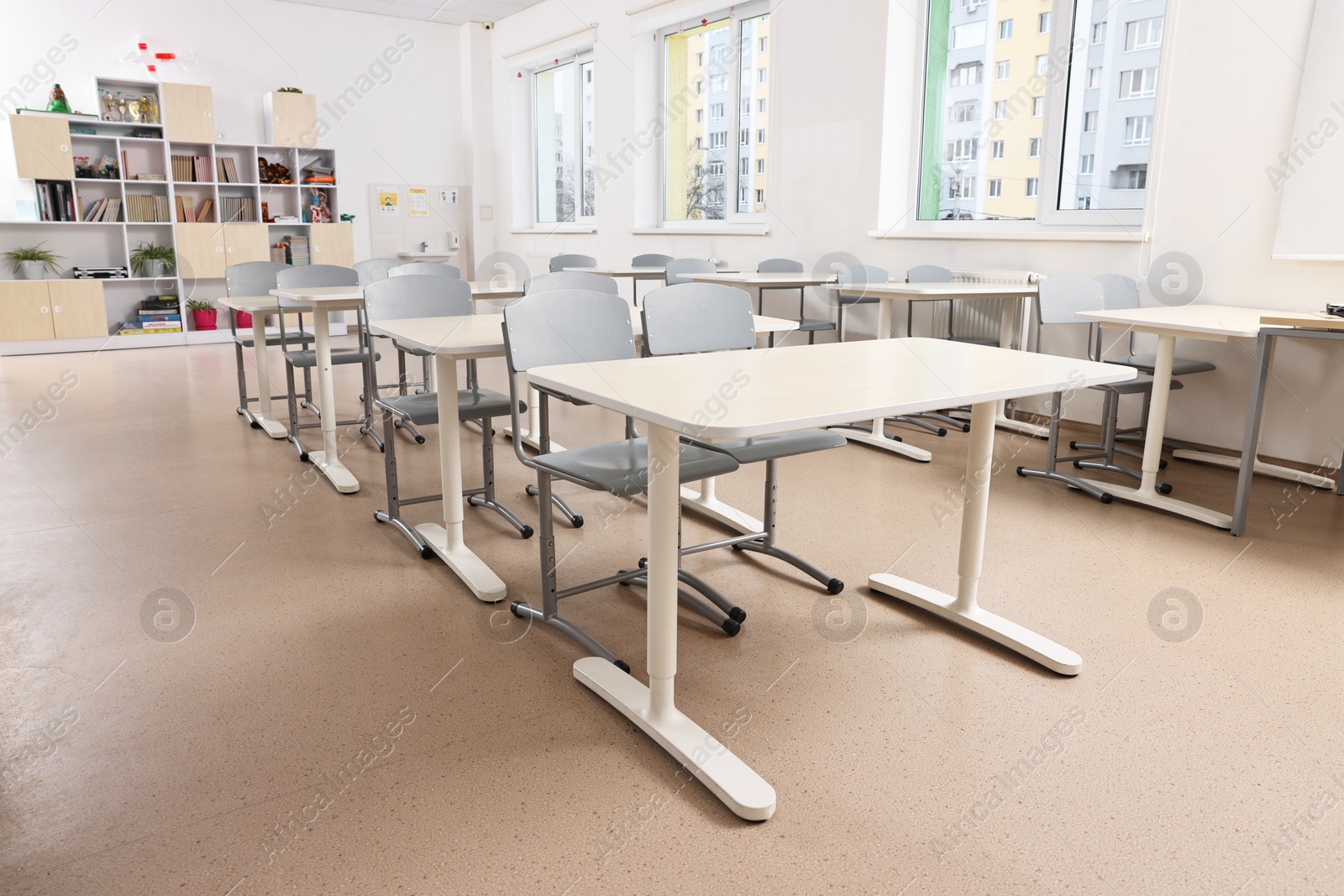 Photo of Empty school classroom with contemporary furniture and windows