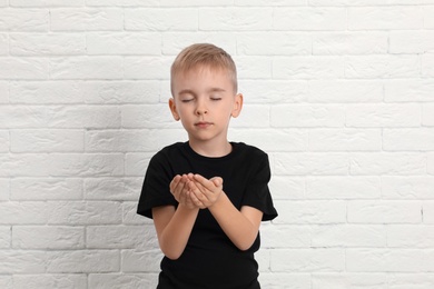 Photo of Little Muslim boy praying near brick wall