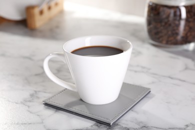 Photo of Delicious coffee in cup on white marble table, closeup