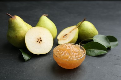 Photo of Tasty homemade pear jam and fresh fruits on black table