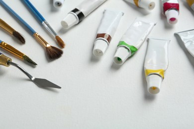 Brushes, spatula and paints on blank canvas, closeup