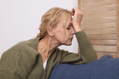 Upset middle aged woman sulking on sofa at home. Loneliness concept