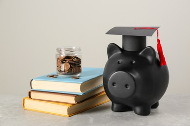 Scholarship concept. Piggy bank, graduation cap, books and coins on light grey table