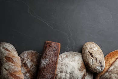 Different kinds of delicious bread on black table, flat lay. Space for text