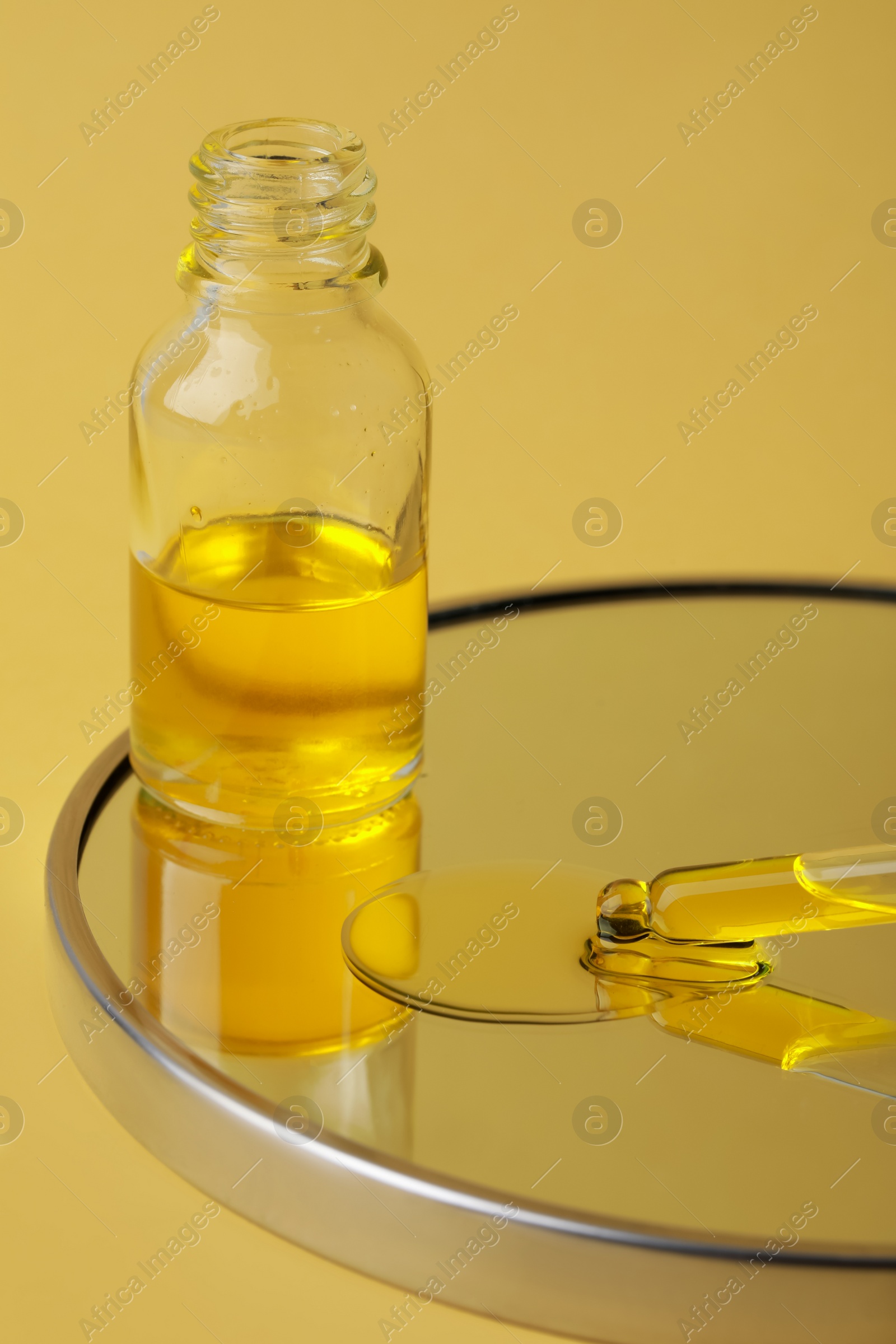 Photo of Bottle of face serum on mirror against yellow background