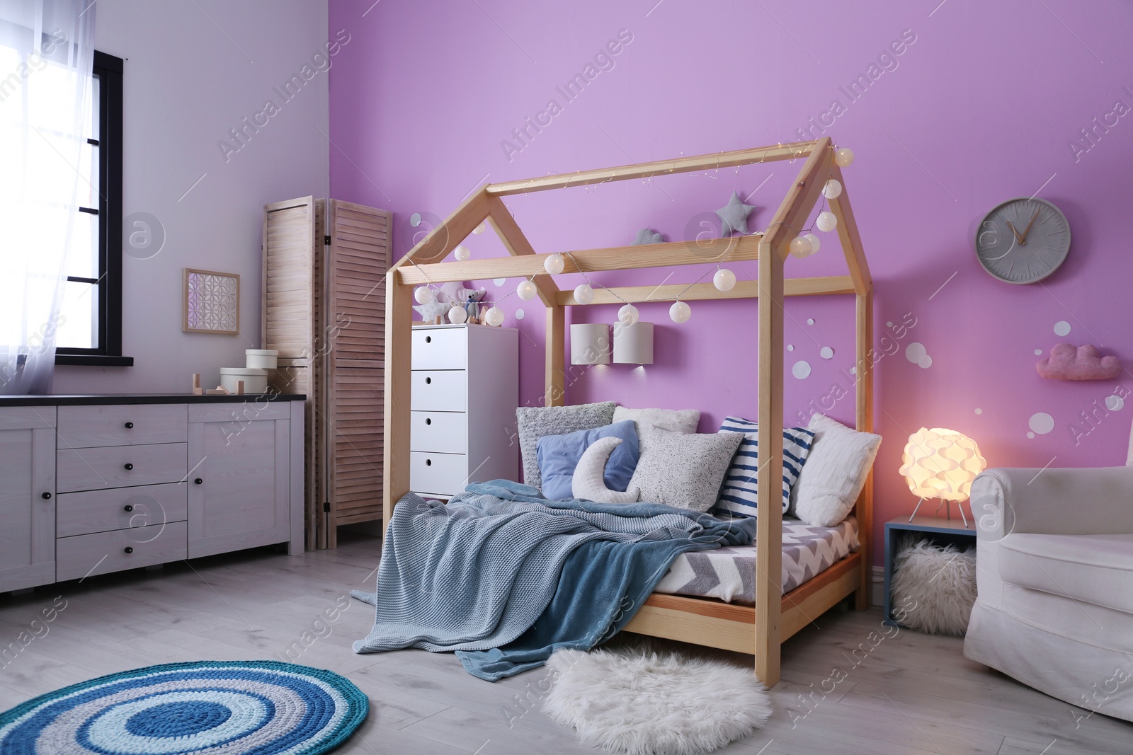 Photo of Child's room interior with comfortable bed and garland