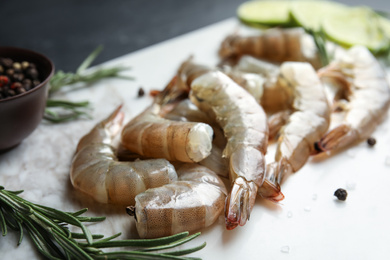 Photo of Fresh raw shrimps with rosemary and pepper on marble board, closeup