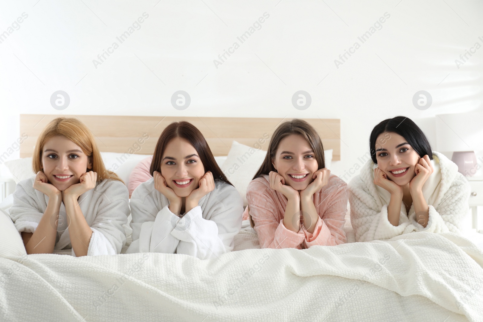 Photo of Beautiful young ladies on bed at pamper party. Women's Day