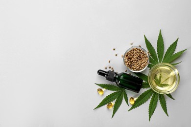 Flat lay composition with CBD oil or THC tincture and hemp leaves on light background, space for text