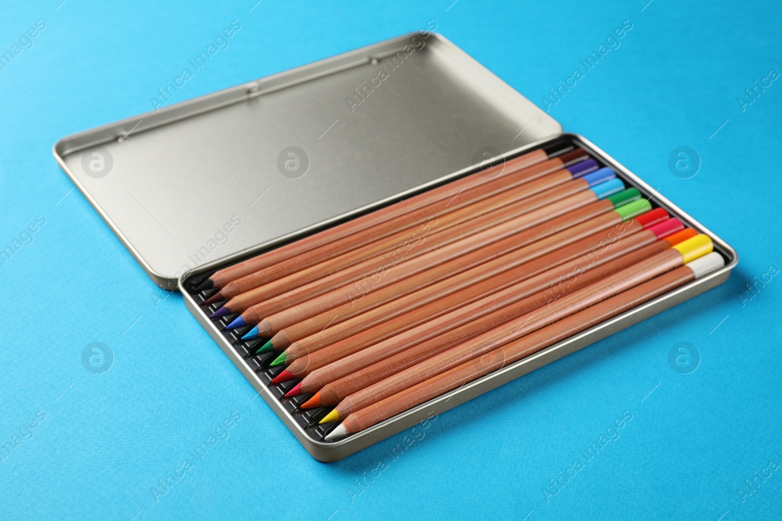 Photo of Box with many colorful pastel pencils on light blue background. Drawing supplies