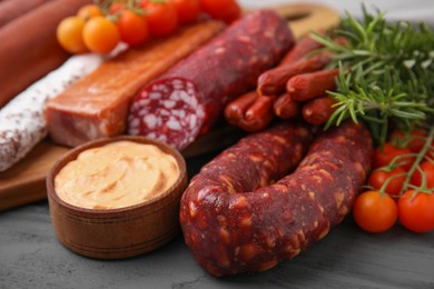 Photo of Different types of tasty sausages on grey wooden table, closeup