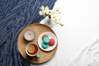 Photo of Flat lay composition with tea and warm plaid on white bedsheet, space for text