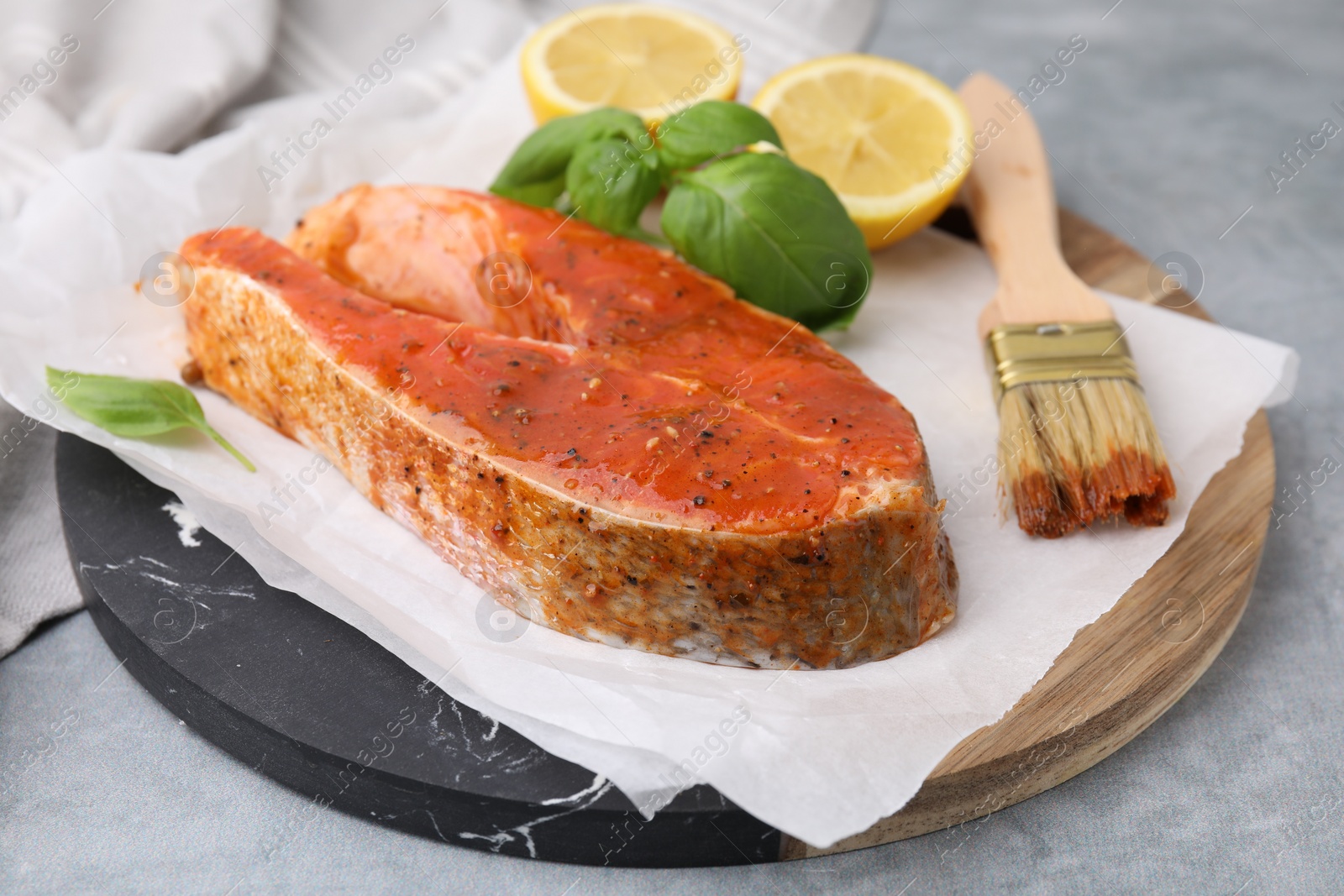 Photo of Fresh marinade, fish, lemon, brush and basil on grey table