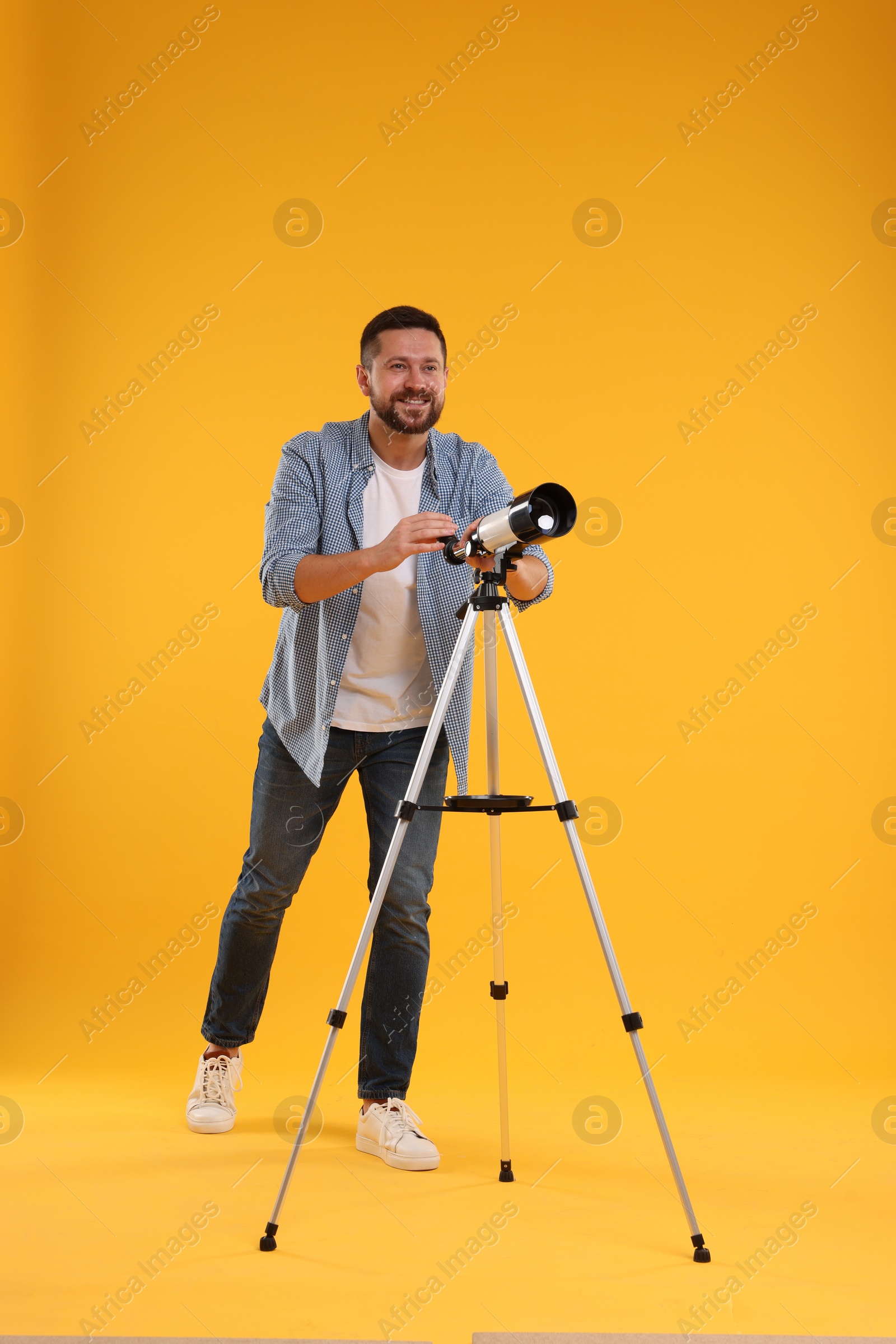 Photo of Happy astronomer with telescope on orange background