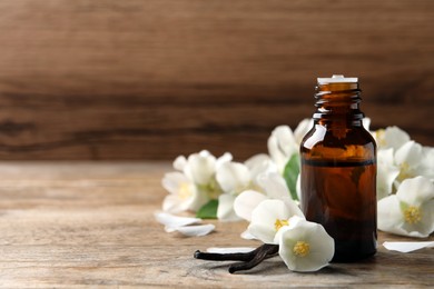 Jasmine essential oil and fresh flowers on wooden table, space for text