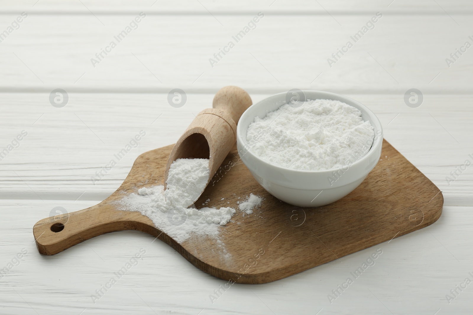 Photo of Baking powder in bowl and scoop on white wooden table