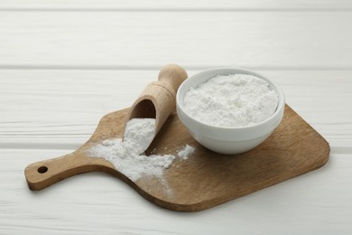 Baking powder in bowl and scoop on white wooden table