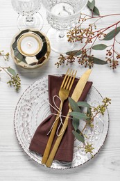 Photo of Stylish table setting with cutlery, burning candle and eucalyptus leaves, flat lay
