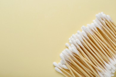 Many wooden cotton buds on beige background, flat lay. Space for text