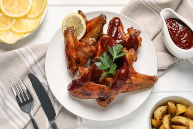 Photo of Delicious fried chicken wings served on white wooden table, flat lay