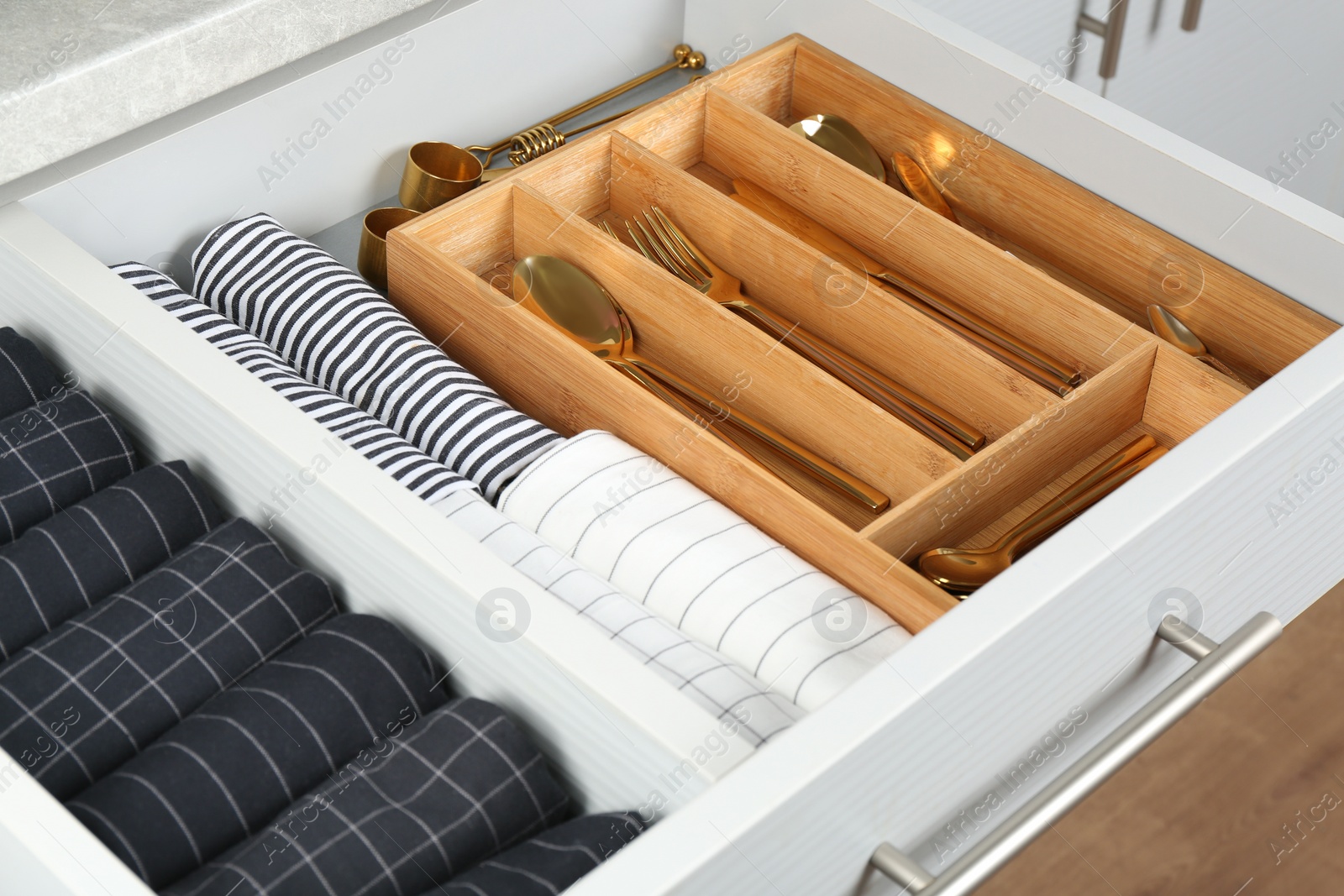 Photo of Open drawer with different utensils and folded towels. Order in kitchen