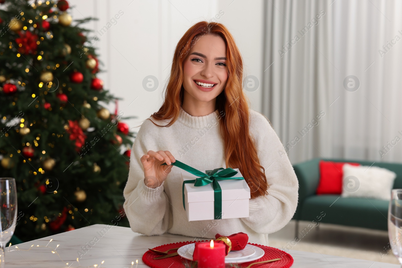 Photo of Beautiful young woman with Christmas gift at home