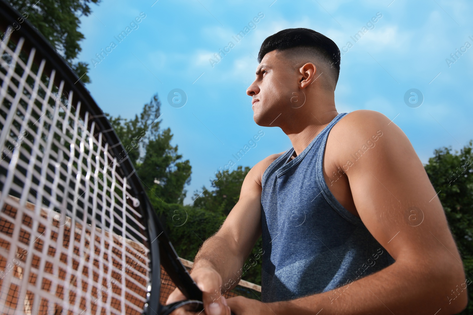 Photo of Man with tennis racket at court, low angle view